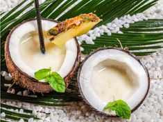 two coconuts are sitting on some white rocks and one has a straw in it