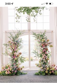 two floral arrangements in front of an open window with greenery and flowers on them