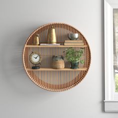 a wall mounted shelf with various items on it and a clock in the middle, next to a window