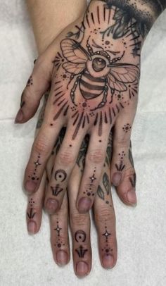 a woman's hand with tattoos on it and a bee tattooed on the palm