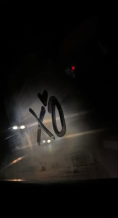 the word xo is spelled out in front of a car's headlights at night