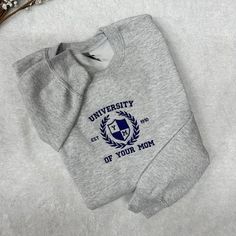 "University of Your Mom embroidered on a crewneck sweatshirt.   In the personalization section write the thread color of the embroidery  The sweatshirt is a soft spun crewneck and is very soft cotton poly blend, which is so comfy. Embroidered text will be as shown as in the picture. Extra personalization is NOT included.  The \"Extra Embroidery Add On\" is available for purchase in our shop if you would like to add any names, initials, etc. Please choose your thread color in the Personalization University Of Your Mom Sweatshirt, University Of Your Mom, Mom Joke, University Hoodies, College Sweater, Embroidered Text, University Crewneck, University Hoodie, Blank Sweatshirts