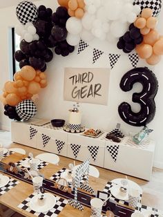 a table topped with black and white balloons next to a sign that says third gear