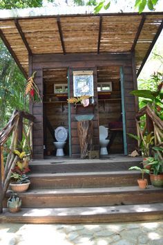 a small wooden cabin with potted plants on the steps