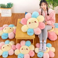 a woman sitting on top of a wooden floor next to many stuffed animals and plants