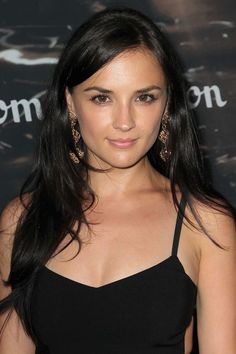 a woman with long black hair wearing large gold earring's at an event