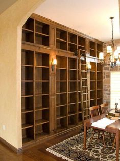 a dining room table and chairs in front of a bookshelf with many shelves