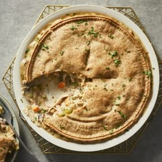 a pie sitting on top of a white plate next to a fork and bowl filled with food