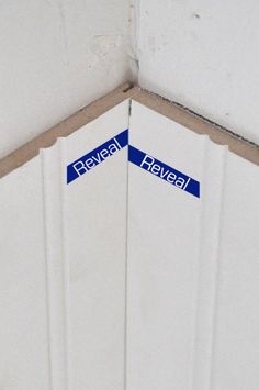 two blue street signs sitting on the side of a white wall next to each other