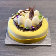 a cake with chocolate and white eggs in a nest on top of a yellow plate