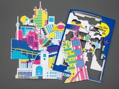 two pieces of paper cut out to look like cityscapes