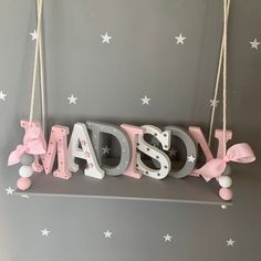 a sign that says made with pink and white letters hanging from strings on a wall