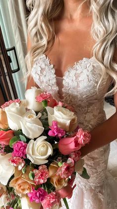 a woman in a wedding dress holding a bridal bouquet with pink and white flowers