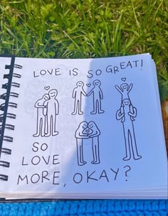 an open notebook with drawings on it sitting in the grass next to a pair of scissors