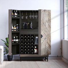 a cabinet with wine glasses and bottles in it next to a potted plant on the floor