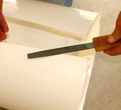 a person cutting something with a knife on top of a piece of white paper that has been cut in half