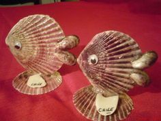 two glass fish figurines sitting on top of a red cloth covered tablecloth