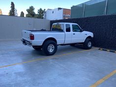 a white pick up truck parked in a parking lot next to a black privacy fence