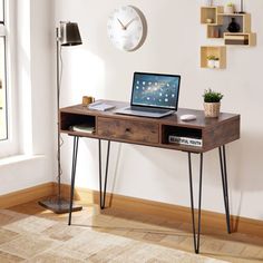 a laptop computer sitting on top of a wooden desk in front of a wall mounted clock