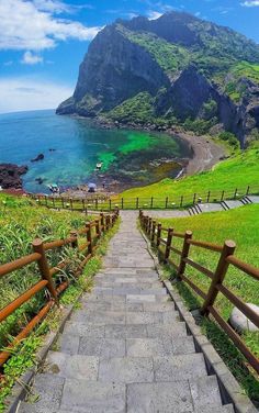 stairs lead down to the beach with mountains in the backgrouds and blue water