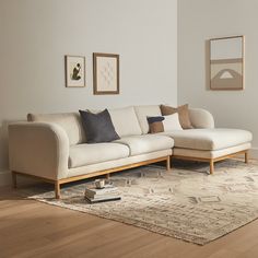 a white couch sitting on top of a wooden floor in a living room next to a rug