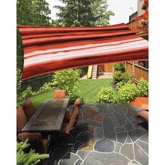 an outdoor dining area with table and chairs under a large red awning over it