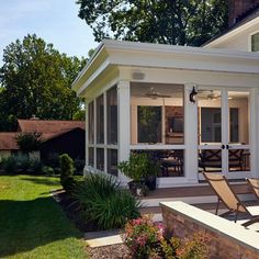 a white house with two chairs on the front porch and one sitting in the back yard