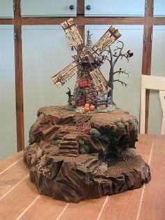 a wooden table topped with a statue of a windmill on top of a rock formation