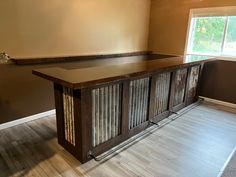 an empty room with a wooden bar in the middle and hard wood flooring on the other side