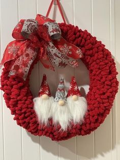 a red wreath with two gnomes hanging on it