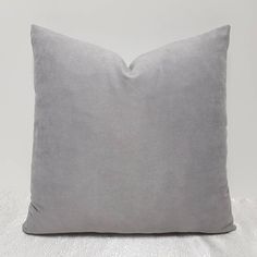 a grey pillow on a white surface