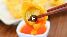 chopsticks holding up some food in front of a bowl full of dipping sauce