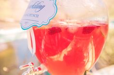 a glass filled with liquid and strawberries sitting on top of a table next to a sign