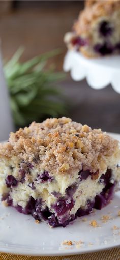 a piece of blueberry crumb cake on a white plate next to a fork