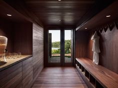 a room with wooden walls and flooring that has wine glasses on the counter, along with a robe hanging from the wall