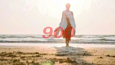 a woman standing on top of a sandy beach next to the ocean