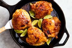 chicken thighs in a skillet with limes on the side