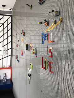 legos are arranged on the wall in this playroom with gray and white walls