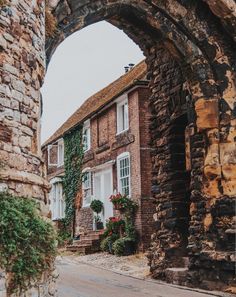 an arch in the side of a brick building with flowers growing on it's sides