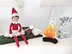 an elf sitting on top of a blanket next to a fire