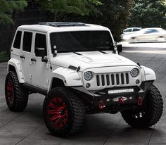 a white jeep with red rims parked in a parking lot