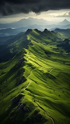 green rolling hills under a cloudy sky with mountains in the backgrounds