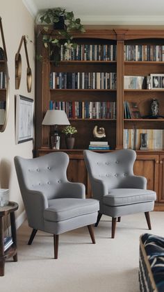 two gray chairs sitting in front of a bookshelf