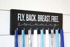 a sign that says fly back, breast free swimming with medals hanging from it's sides