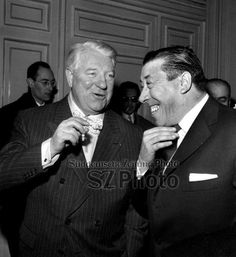 two men standing next to each other in suits