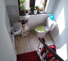 a small bathroom with a green toilet and red rug on the floor, next to a window