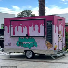 a pink ice cream truck parked in front of a building