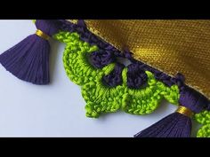 crocheted purple and green tassels hanging from the side of a pillow