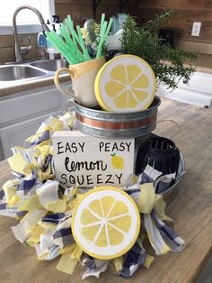 some lemons are sitting in a bucket on top of a kitchen counter next to a sign that says easy peasy lemon squezy