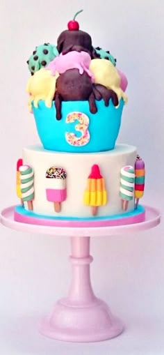 a three tiered cake with ice cream and toppings on the top is decorated in pastel colors